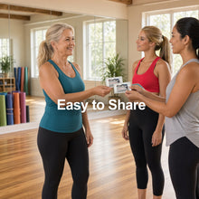 Load image into Gallery viewer, Three women in a bright fitness studio are holding small fitness tracker devices. The woman on the left wears a teal tank top and black leggings, the middle woman wears a red tank top and black leggings, and the woman on the right wears a light gray tank top and black leggings.
